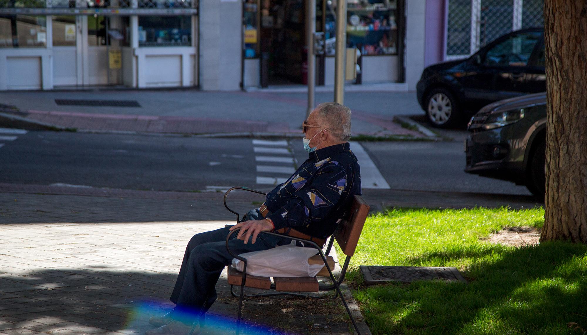 Hombre sentado en parque con mascarilla