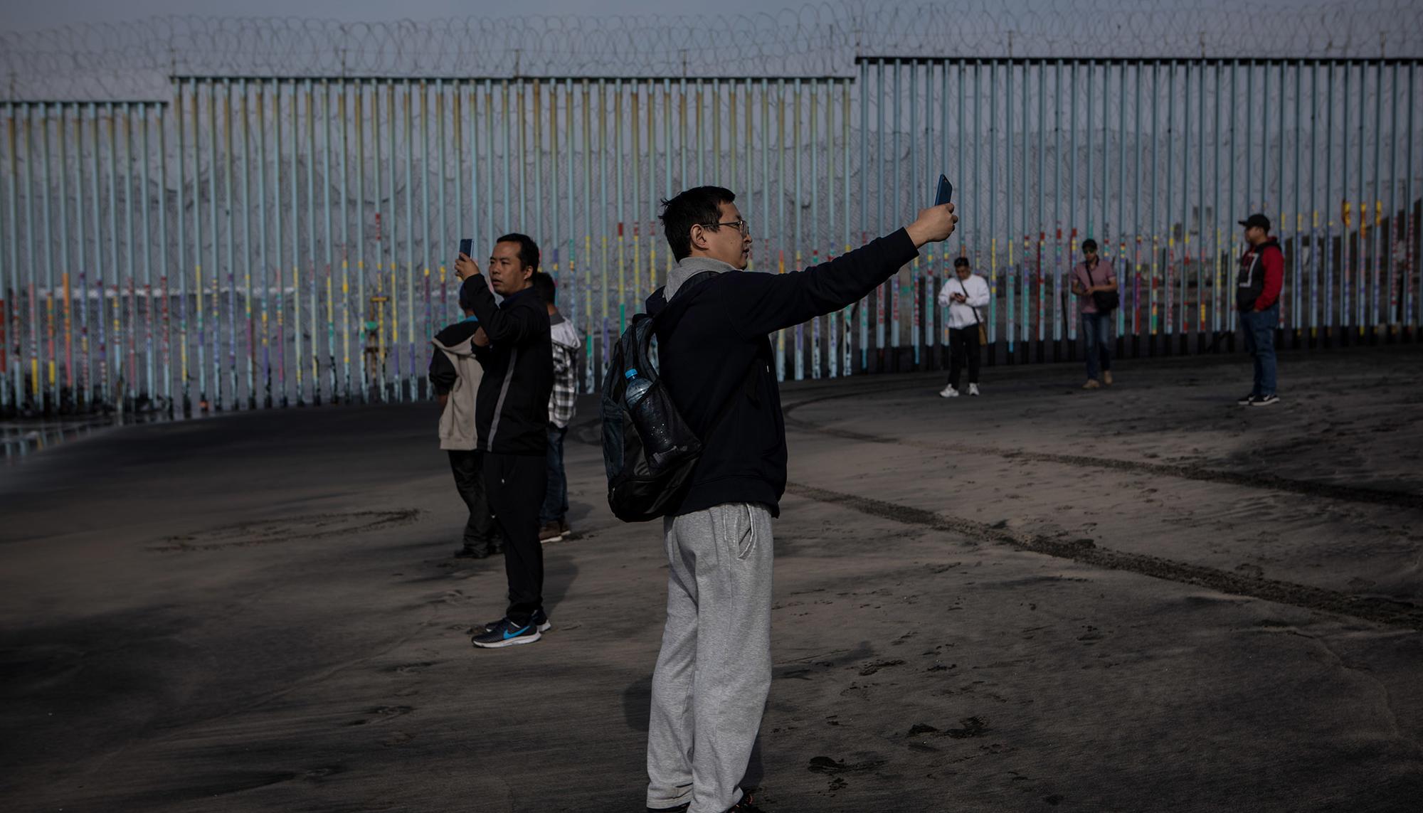 Tijuana. Turistas asiáticos se fotografían junto al muro fronterizo.