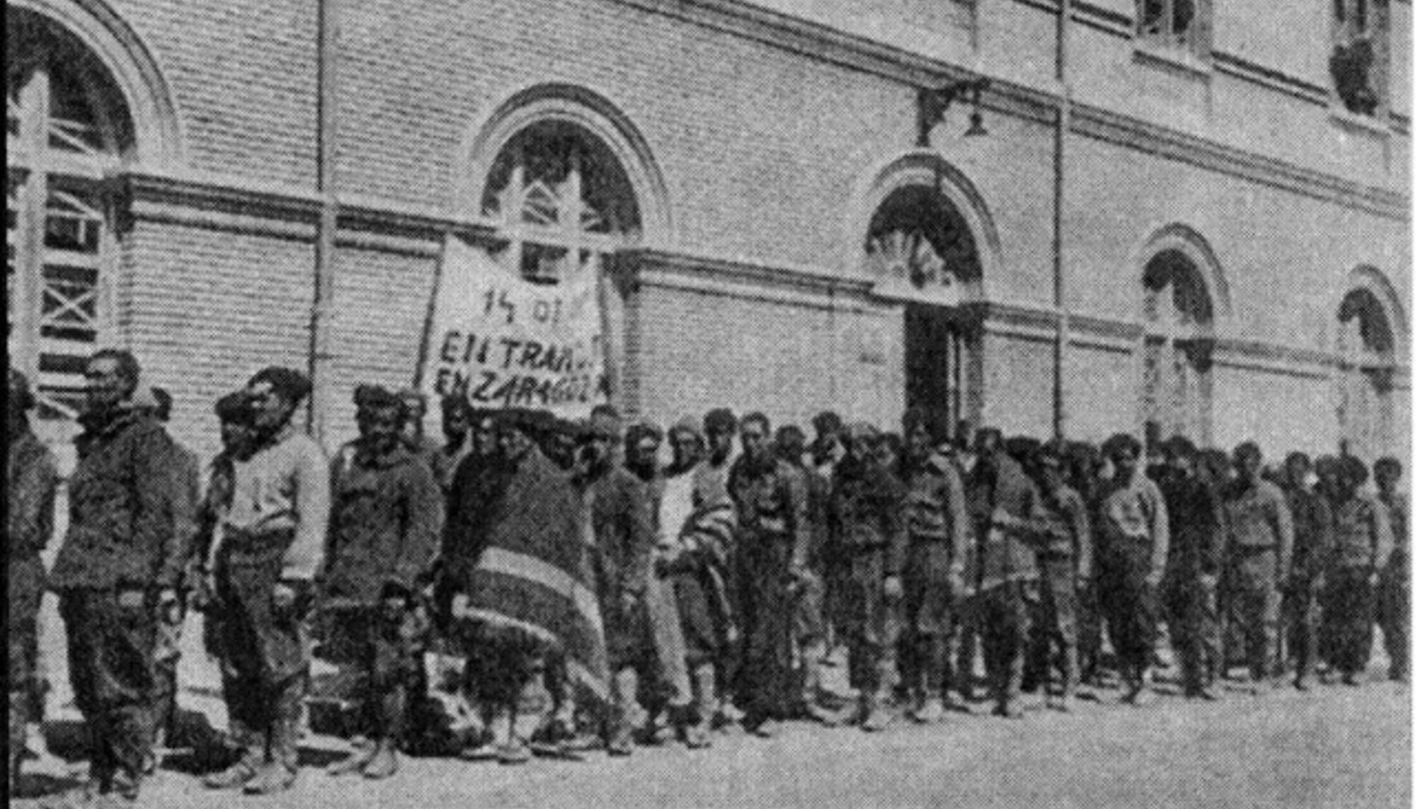 Prisioneros llegando a San Juan de Mozarrifar con un cartel que lee “Entramos en Zaragoza” el 14 de mayo de 1938  