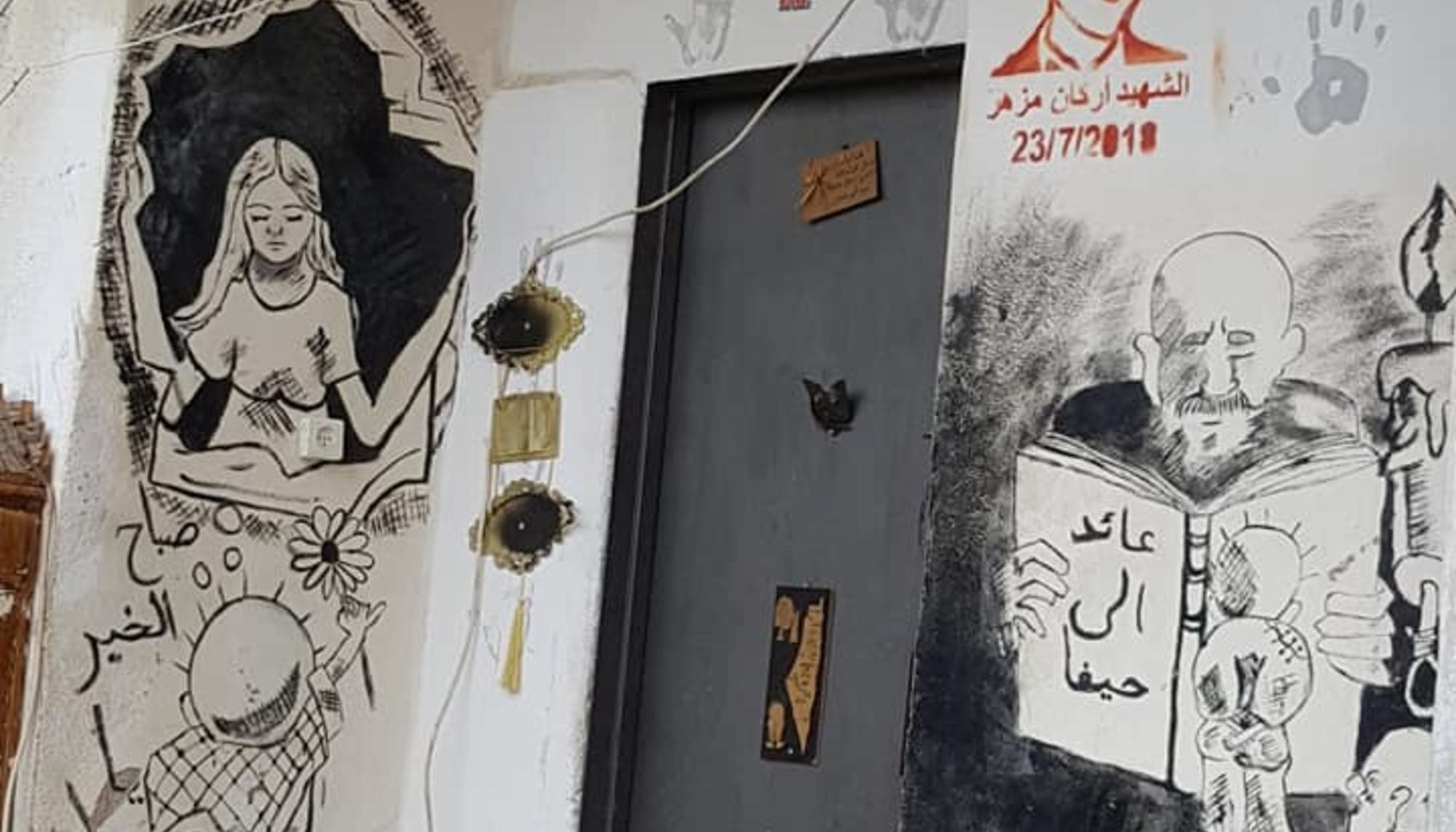 Puerta de una casa en el Campo de refugiados de Dheisheh (Belén) con imágenes del mártir Arkan Mizher y del viñetista Naji Al Ali. Créditos: Badil