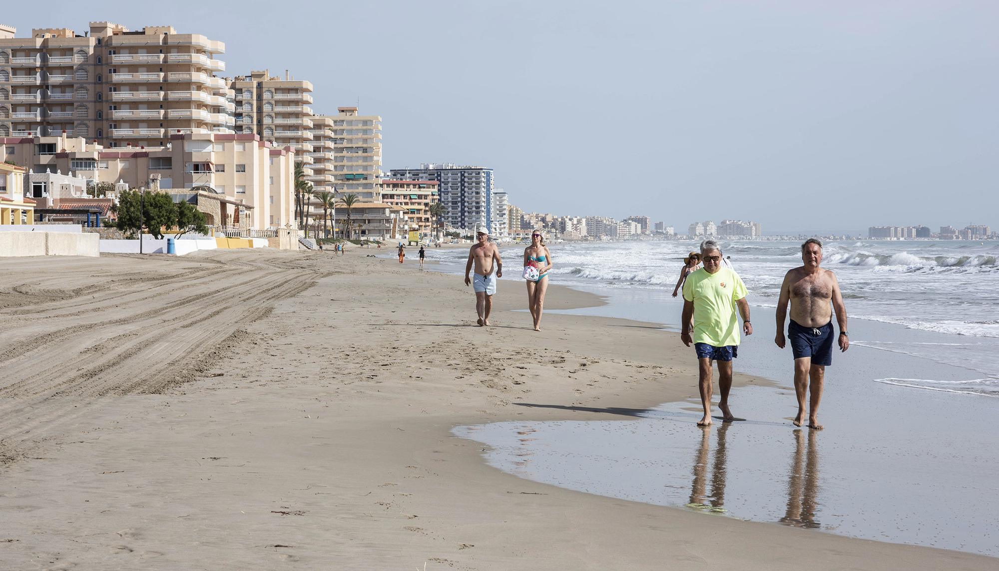 Varios turistas pasean por la playa en La Manga del Mar Menor