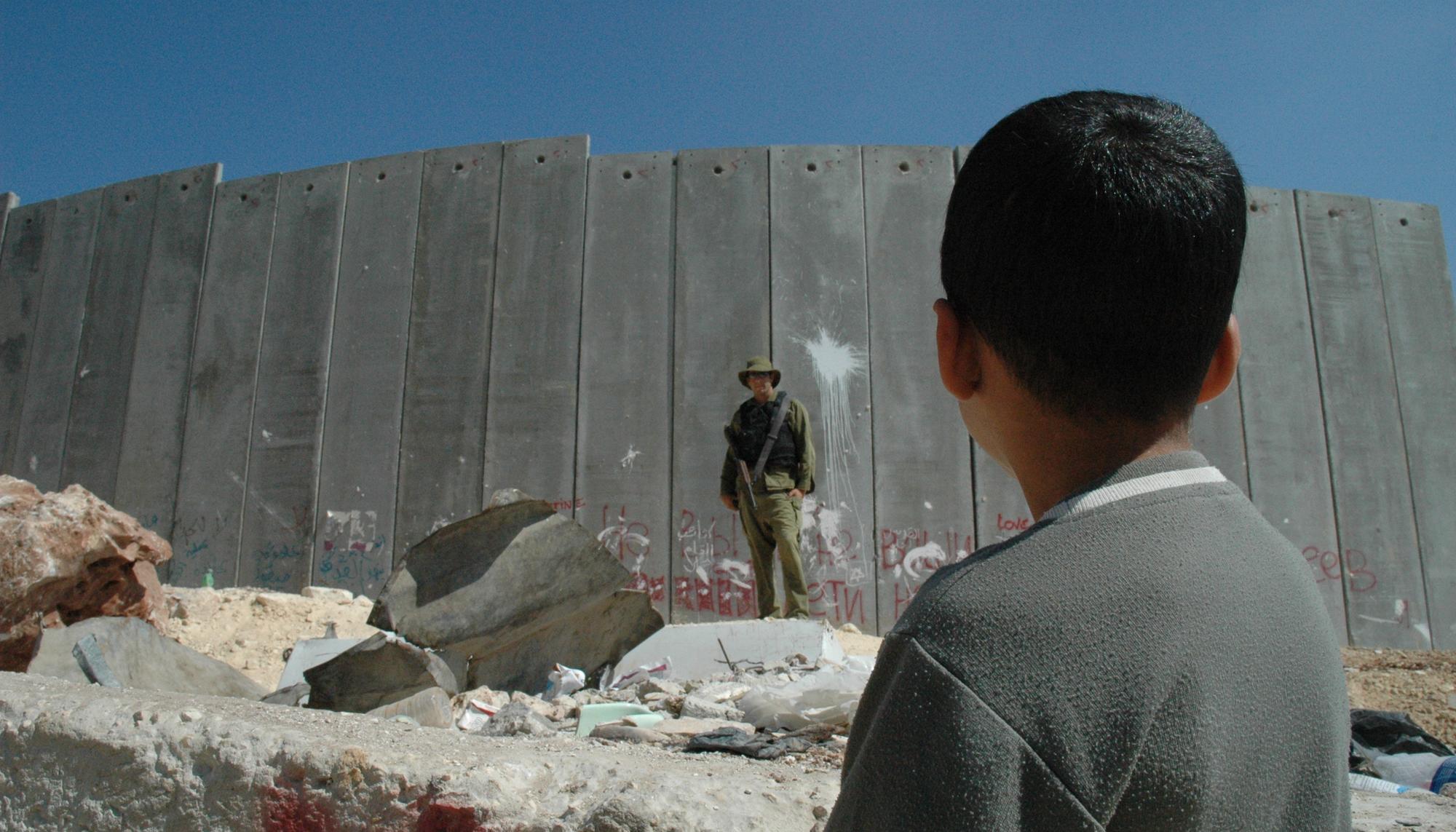 Niño palestino observa a un soldado israelí