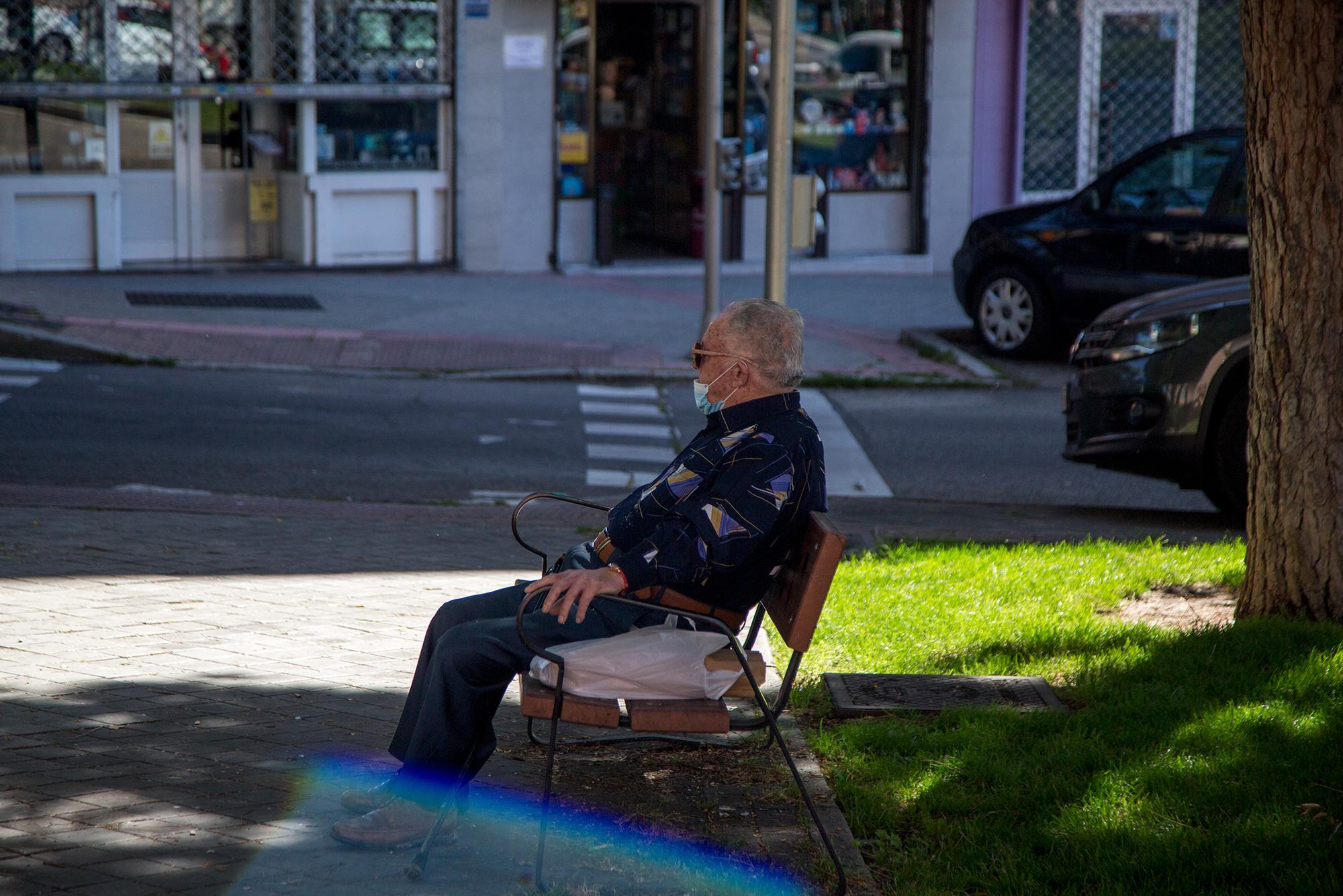 Hombre sentado en parque con mascarilla