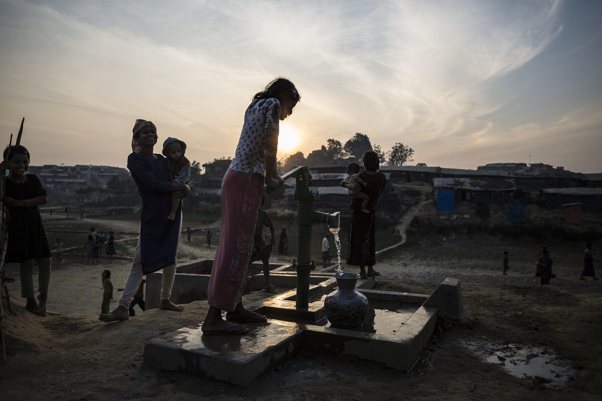 Niña rohingya sacando agua de un pozo.