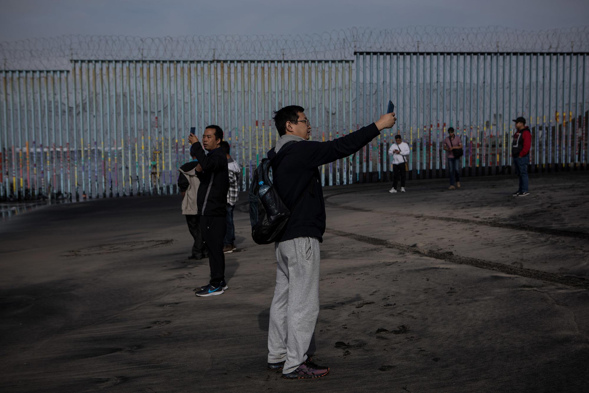 Tijuana. Turistas asiáticos se fotografían junto al muro fronterizo.