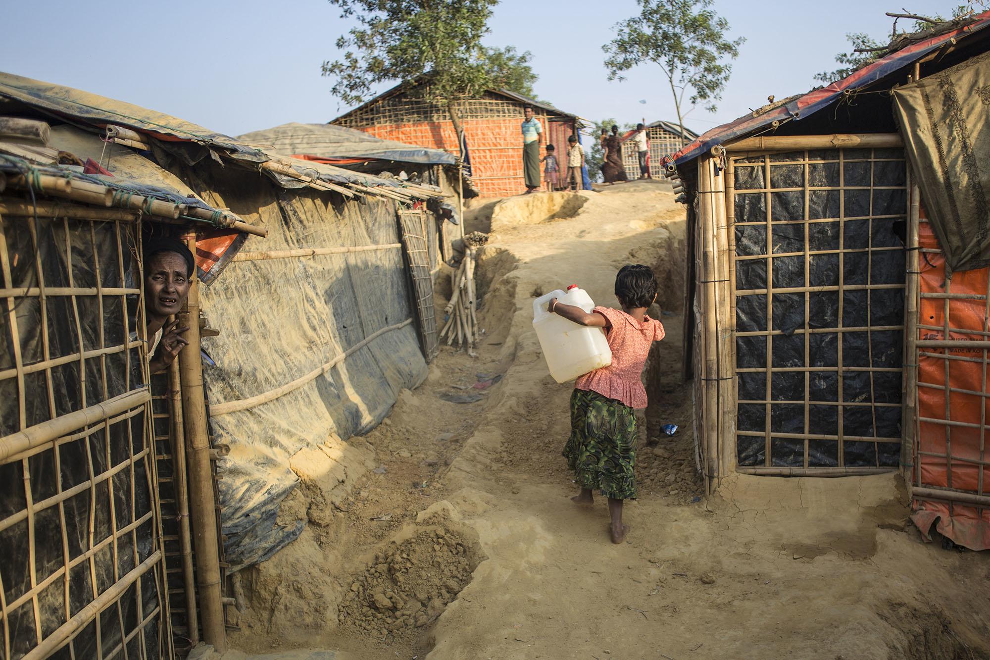 Una niña rohingya transporta un bidón de agua