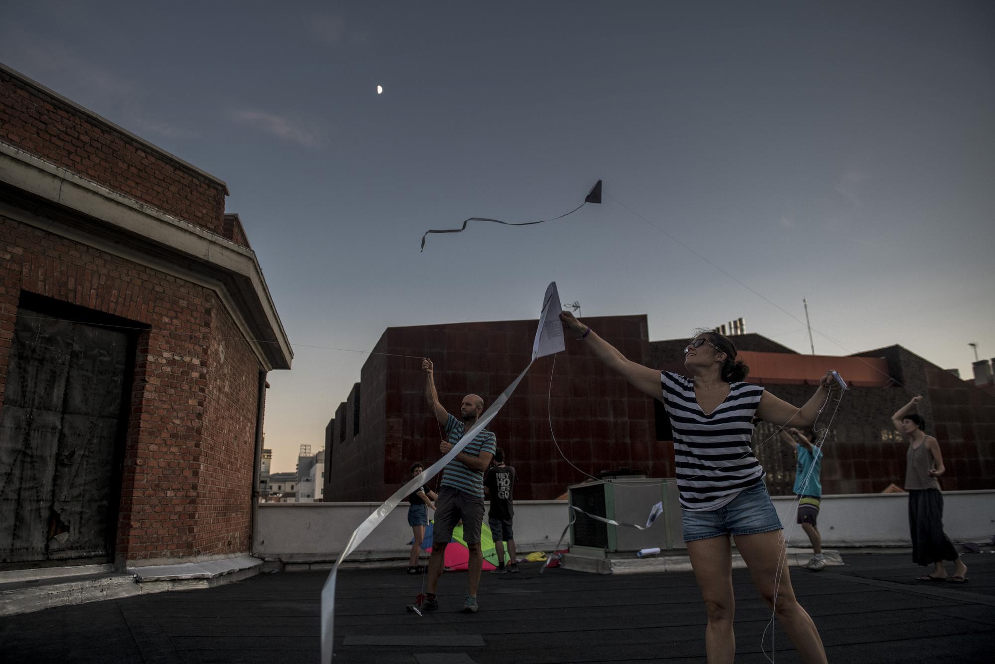 Un grupo de gente volando cometas a la luz del anochecer en la terraza de La Ingobernable