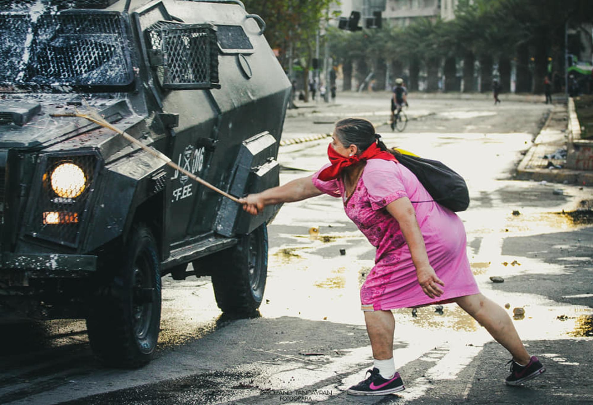 Mujer chilena y carabineros policía, en las protestas contra el gobierno neoliberal de Piñera en Chile, Latinoamérica