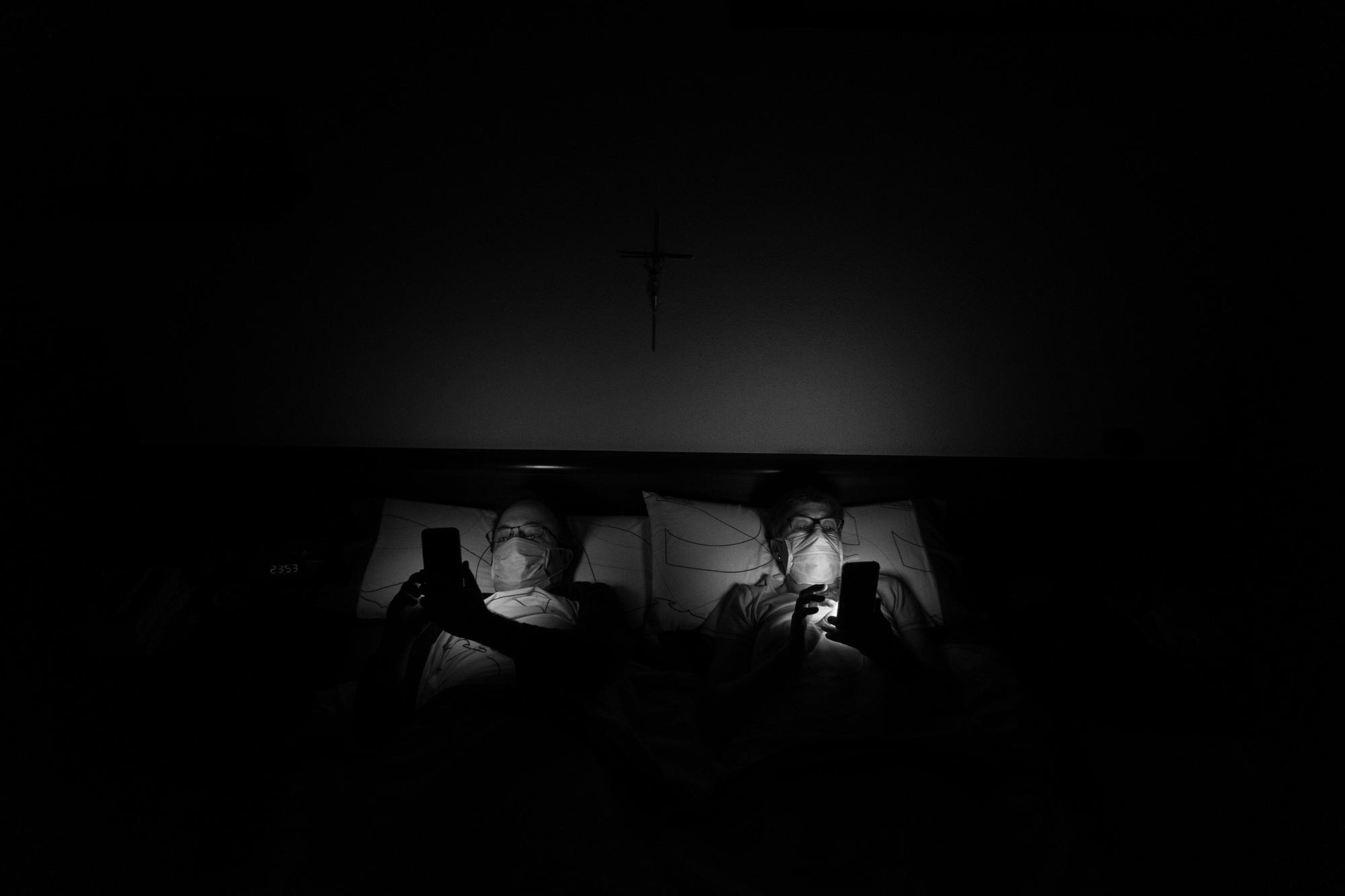 Pareja tumbada con movil y mascarilla