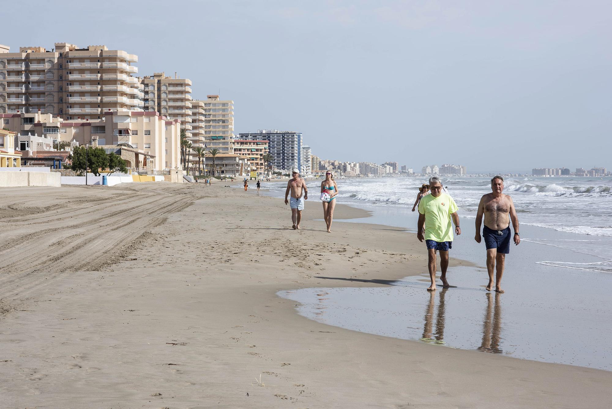 Varios turistas pasean por la playa en La Manga del Mar Menor