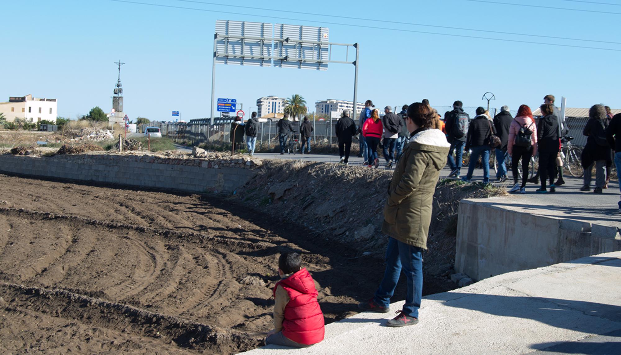 Madre e hijo observan el paso de los participantes del paseo por la huerta de Valencia que será arrasada por la ampliación de la autovía