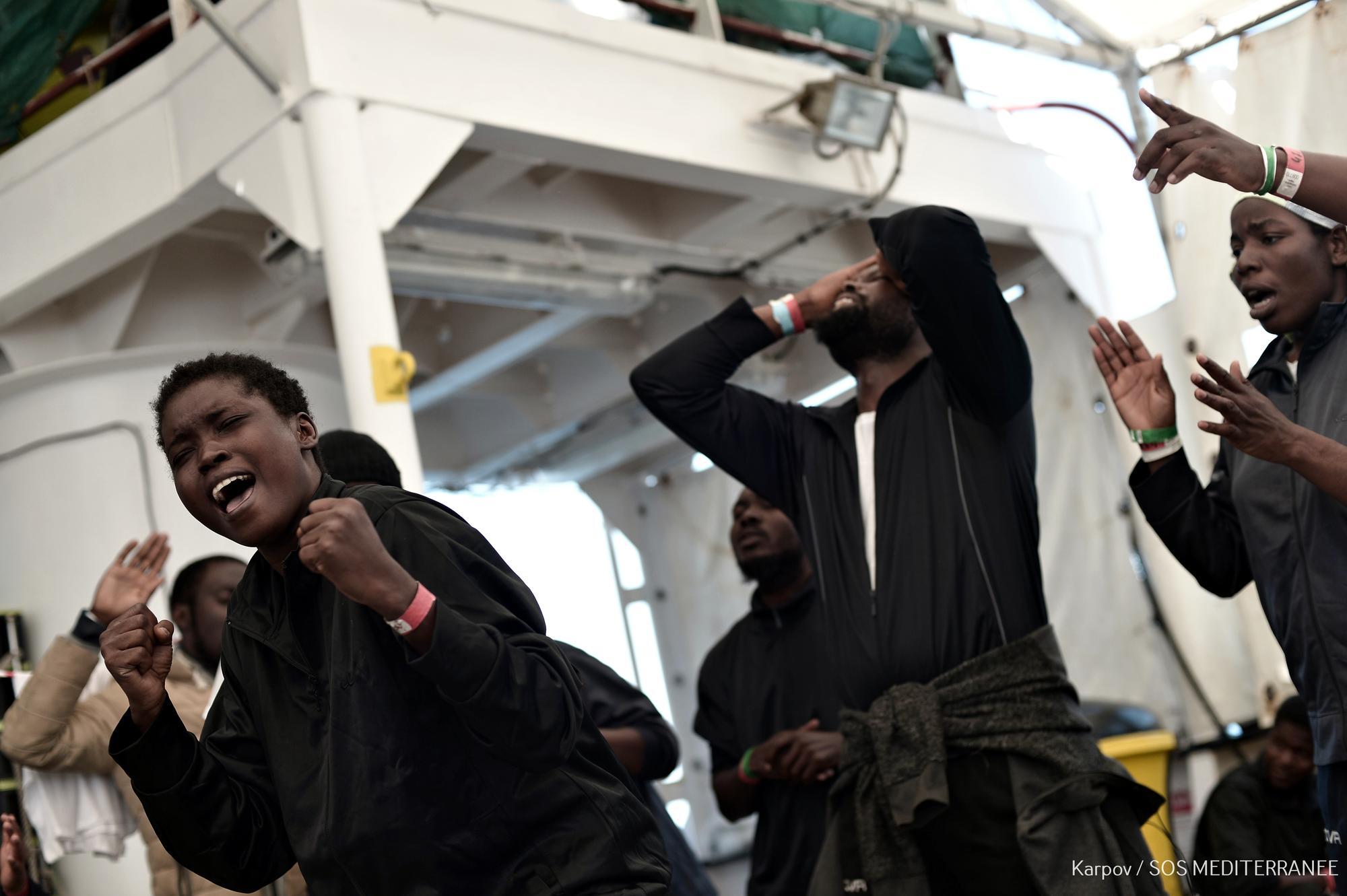 Personas migrantes rescatadas por el Aquarius en las costas de Libia rezan y celebran haber sido llevadas al puerto seguro de València