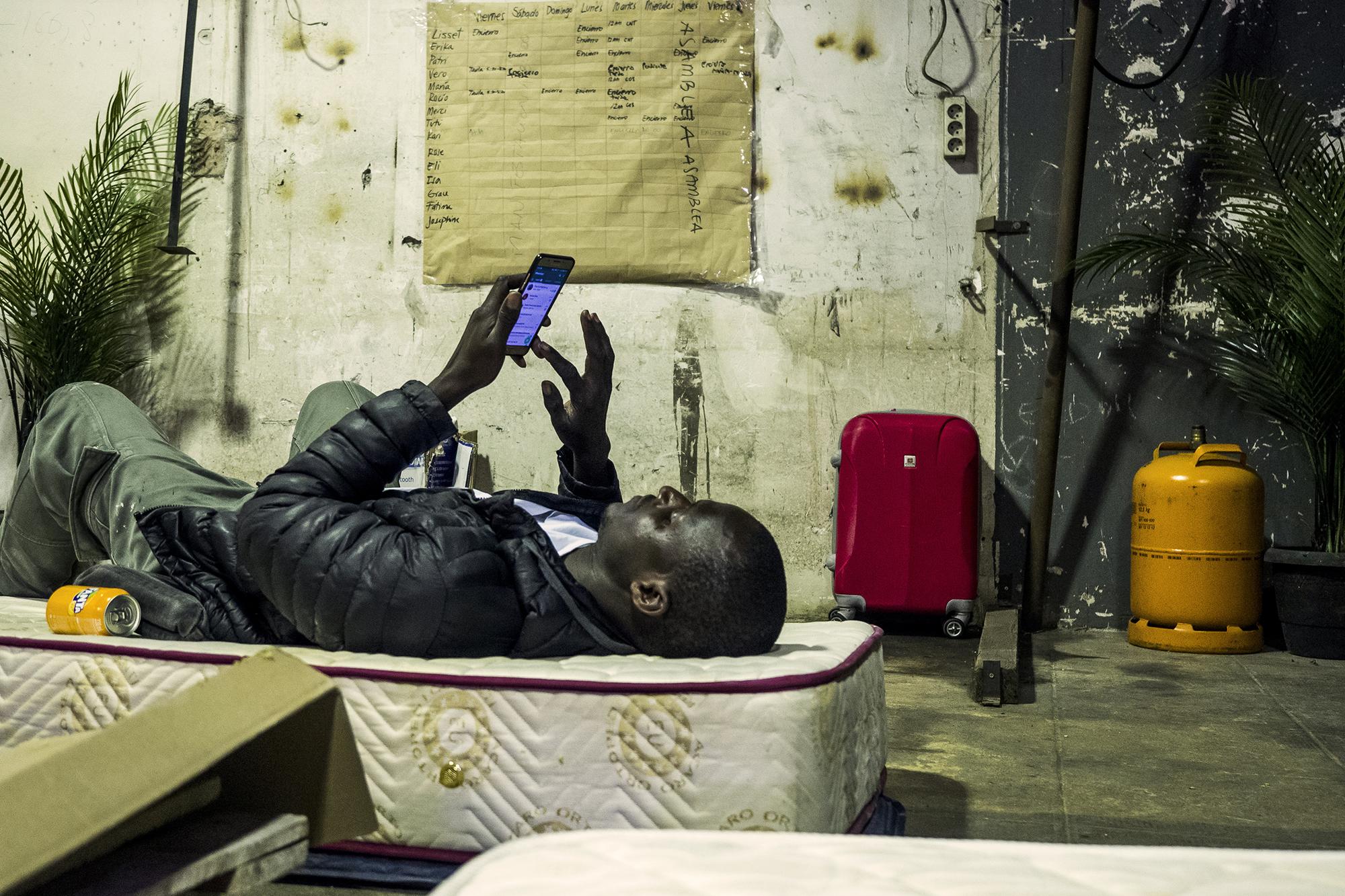 Encierro migrante escuela Massana -joven mirando móvil